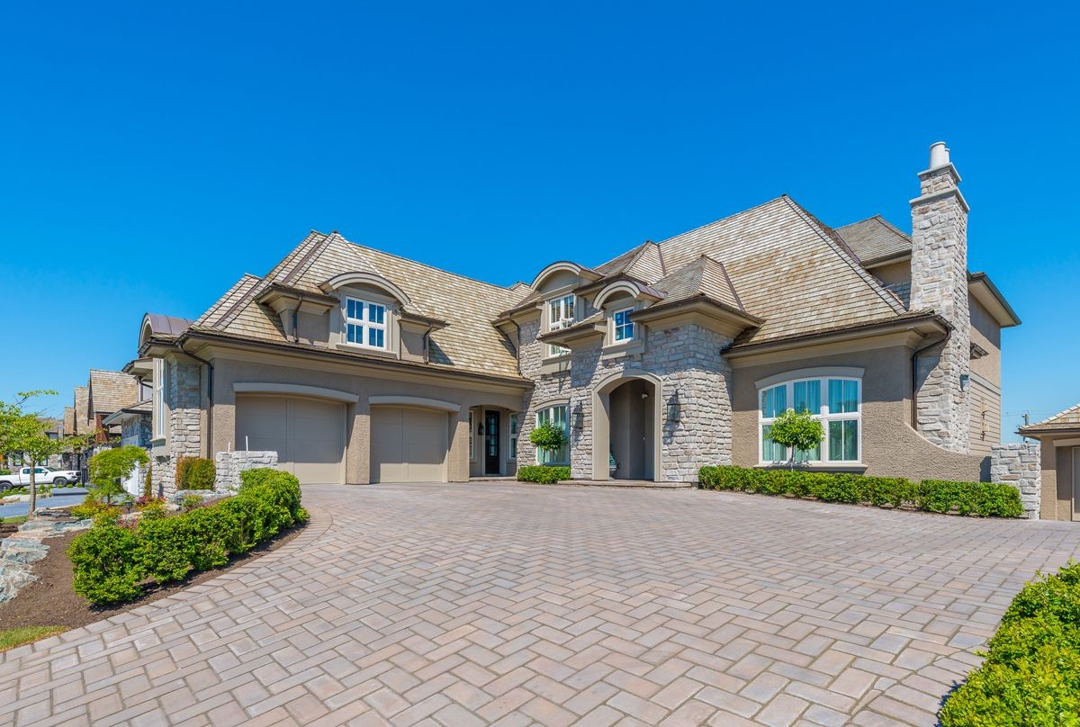 Big custom made luxury house with nicely landscaped and trimmed front yard and driveway to garage in the suburbs of Vancouver, Canada.